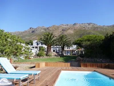 a house with a wooden deck and a swimming pool at Bloemenzee Boutique B&B in Gordonʼs Bay