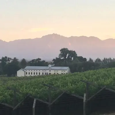 a white barn in a field with mountains in the background at Paarl Mountain Lodge in Paarl