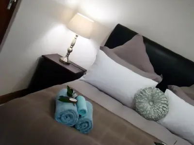 a bedroom with a bed with a lamp and blue towels at Zamar Guest House in Caledon
