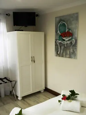 a bedroom with a bed and a cabinet and a television at Zamar Guest House in Caledon