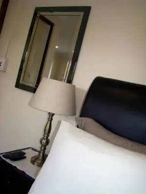 a bedroom with a bed and a lamp and a mirror at Zamar Guest House in Caledon