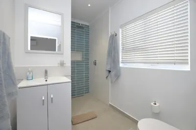 a bathroom with a toilet and a sink and a window at Mossel 11 Studio in Bloubergstrand