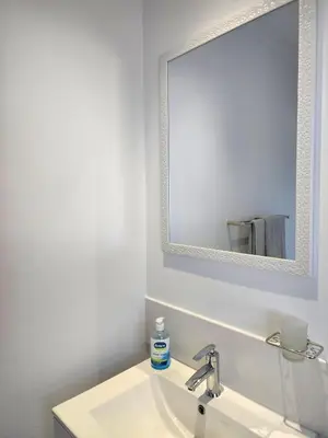 a white bathroom with a sink and a mirror at Mossel 11 Studio in Bloubergstrand
