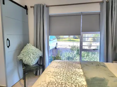 a bedroom with a window with a bed and a chair at Mossel 11 Studio in Bloubergstrand