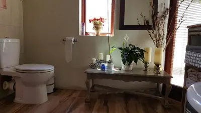 a bathroom with a toilet and a table with candles at Tuckaway in Somerset West