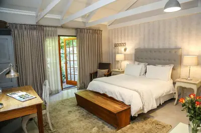 a bedroom with a white bed and a desk and a table at 5 Konings Guesthouse in Paarl