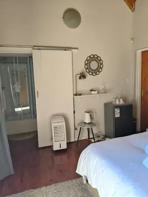 a bedroom with a bed and a table and a window at Lauradale Accommodation in Stellenbosch