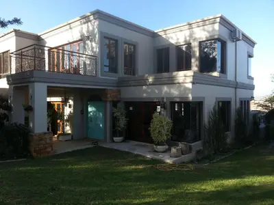 a large white house with a green yard at Die Pastorie in Caledon