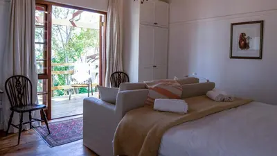 a bedroom with a bed and a sliding glass door at Eastcliff Cottage in Hermanus