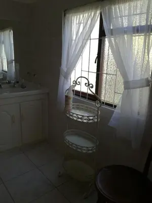 a bathroom with a sink and a window with curtains at Casa Del Mar in Hermanus