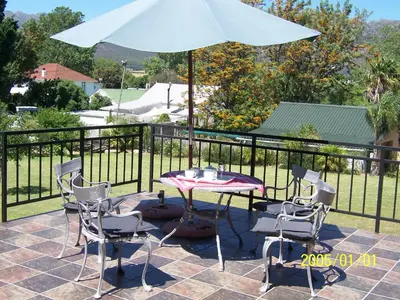 a table and chairs and an umbrella on a patio at Berg en Dal Guesthouse in Villiersdorp