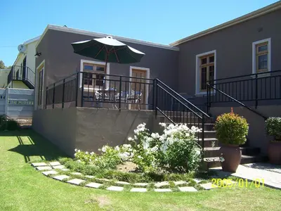 a house with a patio with a table and an umbrella at Berg en Dal Guesthouse in Villiersdorp