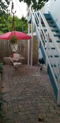 a patio with a red umbrella and a table and a staircase at Cobie Apartment in Stellenbosch