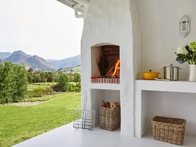 a fireplace in a living room with a view at La Cotte Forest Cottages in Franschhoek