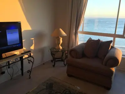 a living room with a couch and a television at Pebble Moon Holiday Flat in Strand