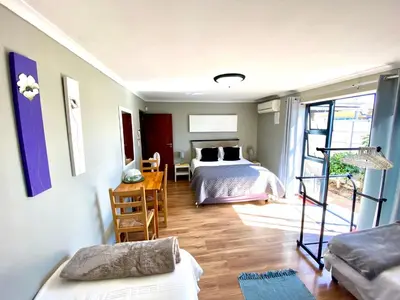 a bedroom with a bed and a desk with a table at Azura Sleep Brackenfell in Brackenfell