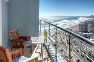 a balcony with a table and chairs and a view of the beach at Horizon Bay 1404 by HMH in Bloubergstrand
