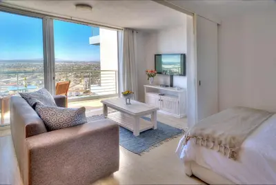 a bedroom with a bed and a couch and a window at Horizon Bay 1404 by HMH in Bloubergstrand