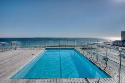 a swimming pool on a deck next to the ocean at Horizon Bay 1404 by HMH in Bloubergstrand