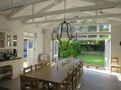 a dining room with a large wooden table and chairs at Vivere in Hermanus