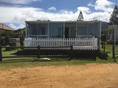 a house with a white fence in front of it at Beach Cottage in Kleinmond