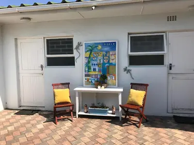 two chairs with yellow pillows sitting in front of a house at Leisure By The Sea in Kleinmond