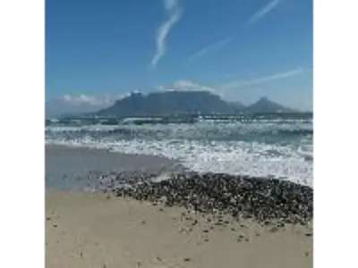 a beach with the ocean and mountains in the background at Blue Mountain Guest House in Bloubergstrand