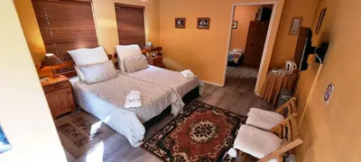 a small bedroom with a bed and a chair at Blue Mountain Guest House in Bloubergstrand