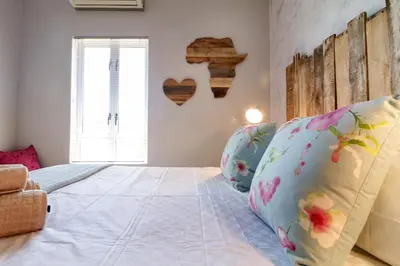 a bedroom with a large bed with two pillows at Modern Shabby Chic Apartment in Durbanville