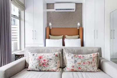 a bedroom with a bed with a couch and pillows at Lux Andringa Walk Apartments in Stellenbosch