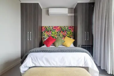 a bedroom with a bed with colorful pillows on it at Lux Andringa Walk Apartments in Stellenbosch