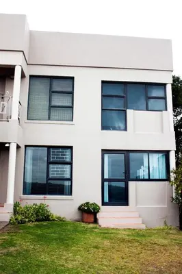 a white house with black windows at Villa De Vie Self Catering Apartment in Brackenfell