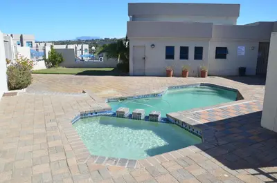 a swimming pool with chairs in front of a house at Villa De Vie Self Catering Apartment in Brackenfell