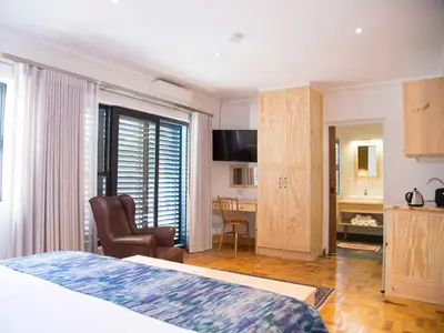 a bedroom with a bed and a desk and a chair at 7 Ackermann Place Guest House in Stellenbosch
