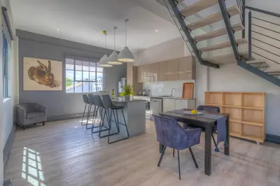 a kitchen and living room with a table and chairs at Crossfire @ Home in Somerset West