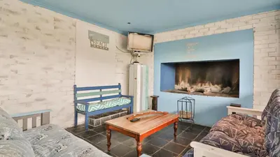 a living room with a table and a fireplace at Da Capo in Bettyʼs Bay