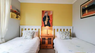 two beds in a room with a painting on the wall at Da Capo in Bettyʼs Bay
