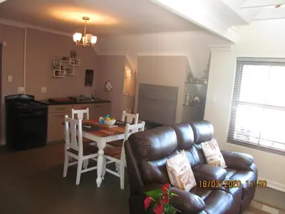 a living room with a couch and a table and a kitchen at Luxury Secure Flat Apartment in Plattekloof