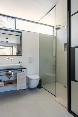 a bathroom with a toilet and a glass shower at La Chataigne Wines & Guest Cottages in Franschhoek