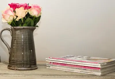 a vase of flowers next to a stack of books at Stellenhaus Guest Cottage in Stellenbosch