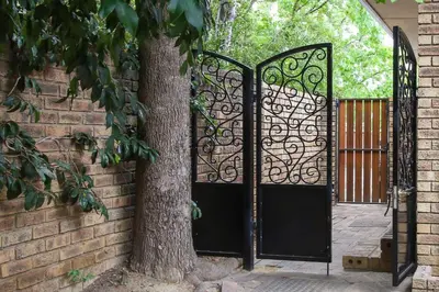 a gate with a tree in front of a brick wall at Stellenhaus Guest Cottage in Stellenbosch