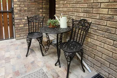 two chairs and a table with a plant on a patio at Stellenhaus Guest Cottage in Stellenbosch