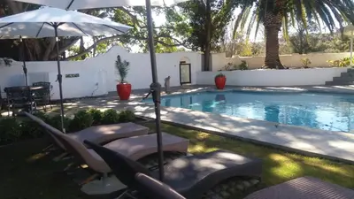 a swimming pool with chairs and an umbrella at Slaley Country House in Stellenbosch