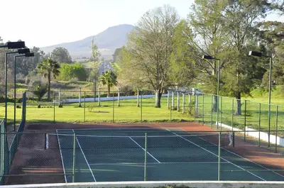a tennis court in a park with a field at Slaley Country House in Stellenbosch