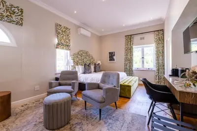a bedroom with a bed and two chairs at Laborie Estate in Paarl