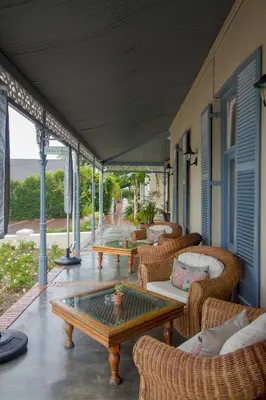 a porch with wicker chairs and a coffee table at Pontac Manor Hotel & Restaurant in Paarl
