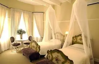 a bedroom with two beds and a table with chairs at Pontac Manor Hotel & Restaurant in Paarl