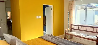 a yellow room with a bed and a window at Charming Fisante house in Hermanus