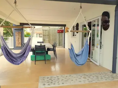 a room with two hammocks and a table and chairs at Charming Fisante house in Hermanus