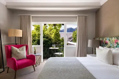 a bedroom with a bed and a chair and a window at Mont Rochelle Hotel and Vineyard in Franschhoek